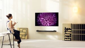 An oled lg tv on a wall with a woman watching it