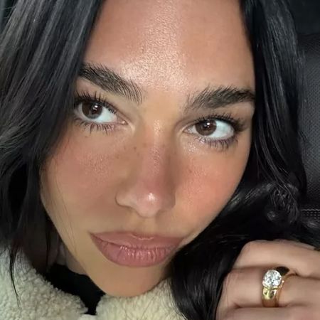 Dua Lipa wears a cream sweater and poses with her huge diamond engagement ring and Dua Lipa hugs rumored fiance Callum Turner