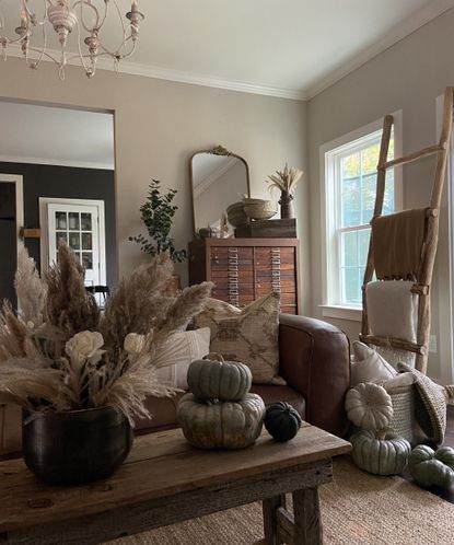 cozy Thanksgiving living room decor with layered throws, blankets and pillows, pumpkins and dried grasses in vases