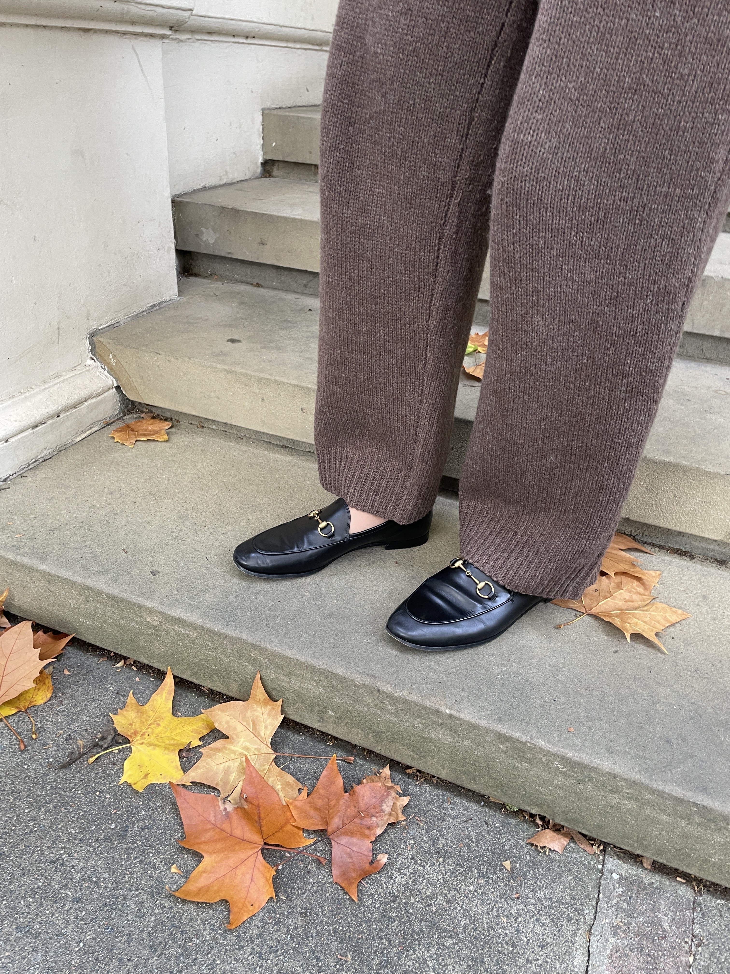 Woman wears brown knit trousers and black Gucci loafers