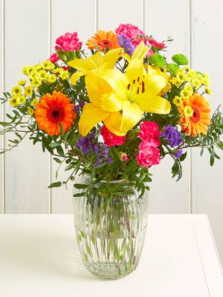 bouquet of bright flowers in glass vase on table