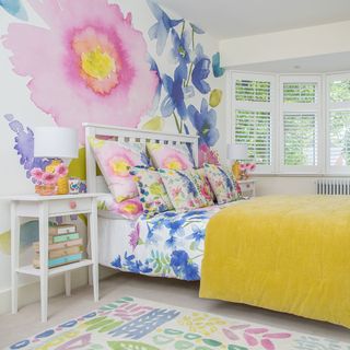 floral bedroom with wallpaper on walls having bed with pillows
