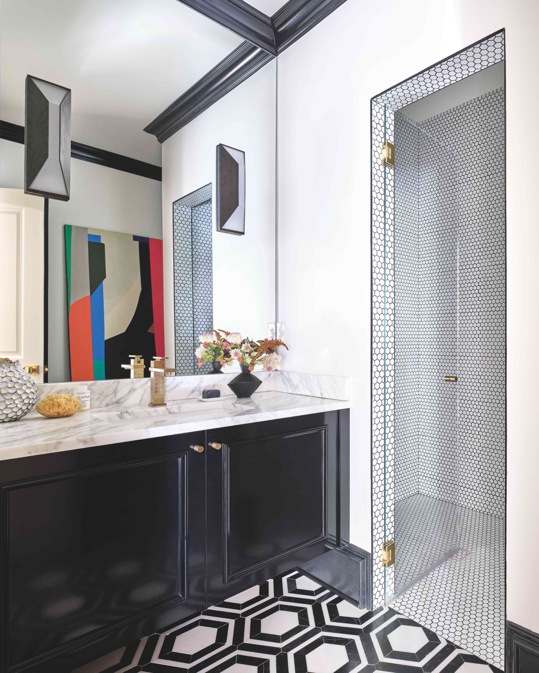 Bathroom with large black-and-white hexagonal floor tiles and a glass shower lined with small white hexagon mosaics and dark grout.