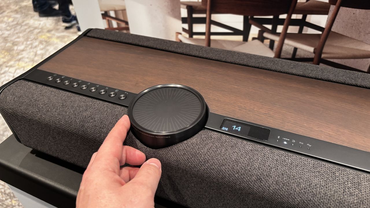 A finger touching the control dial on top of the Dali Vega wireless sound system