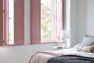 Pretty bedroom with loose linen covers and pink solid window shutters