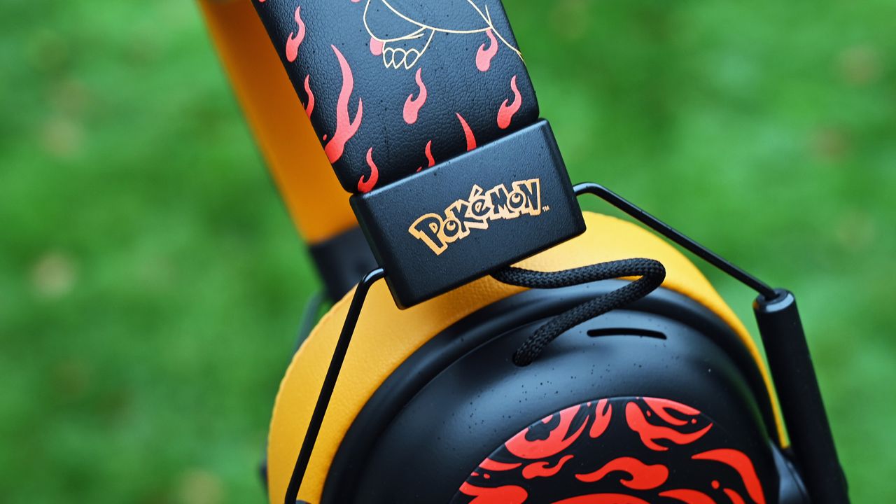 Close-up of the Razer Charizard headset headband featuring red flame graphics, gold line art, and a black hinge piece stamped with the yellow Pok&eacute;mon logo.