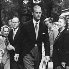 Prince Philip walking past smiling people in a three-piece suit