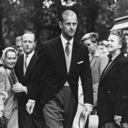 Prince Philip walking past smiling people in a three-piece suit