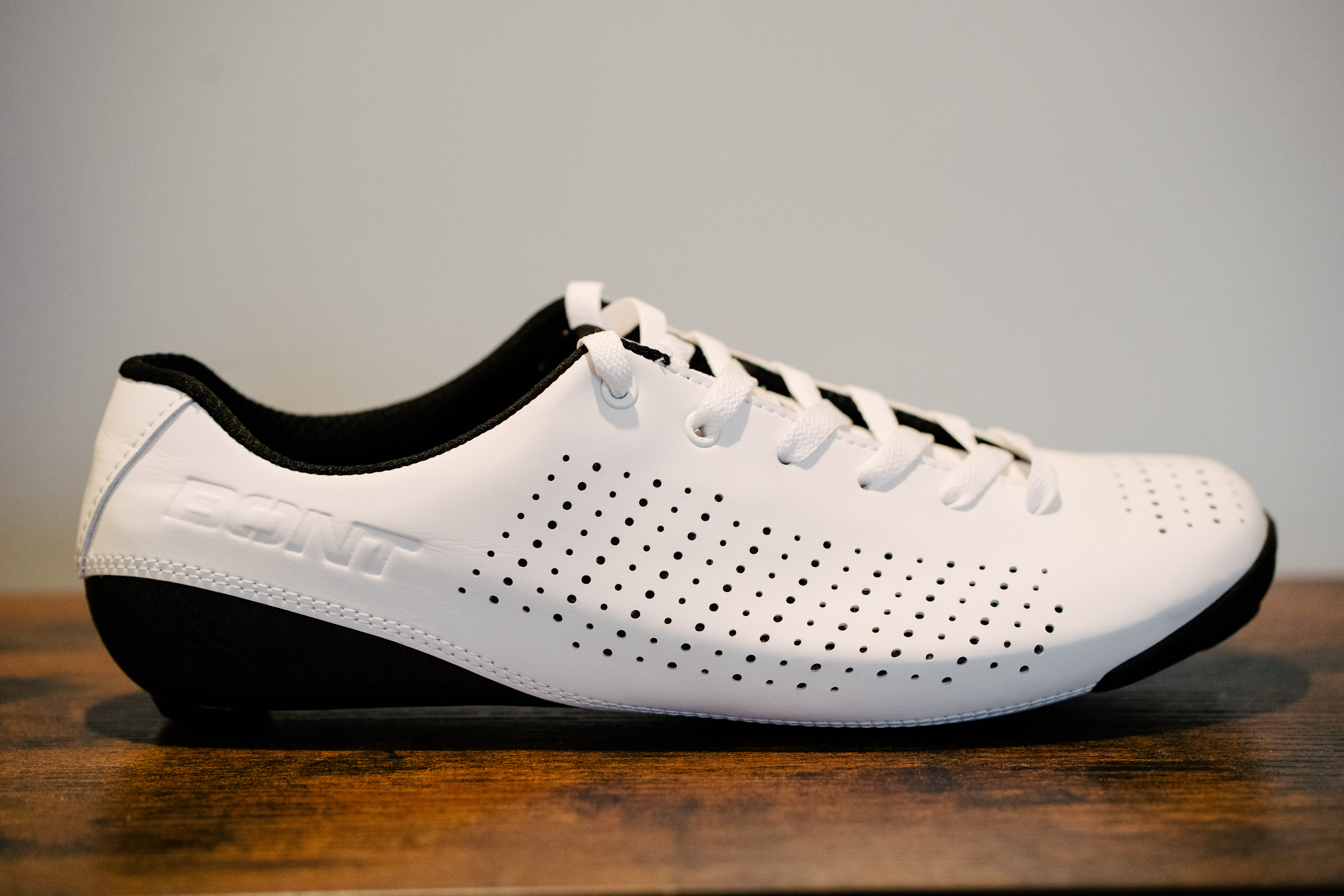 A lace up set of bike shoes on a wooden shelf