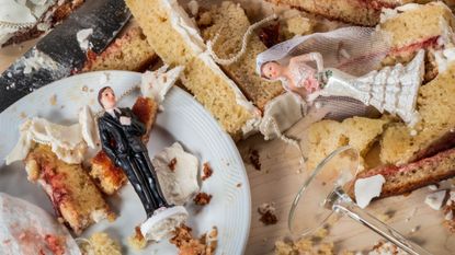 Pieces of wedding cake on a tabletop, with figures of a bride and groom atop them
