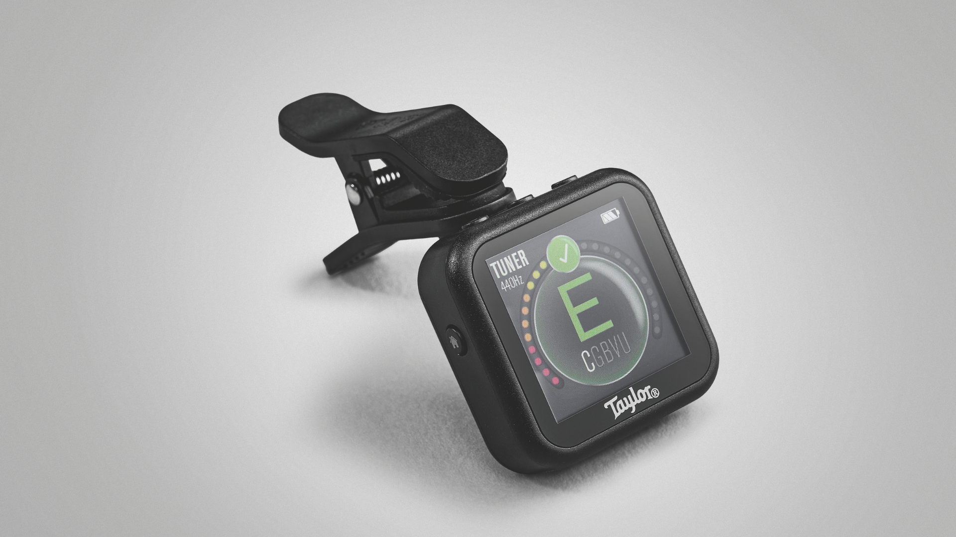 A Taylor Beacon clip on guitar tuner on a gray background