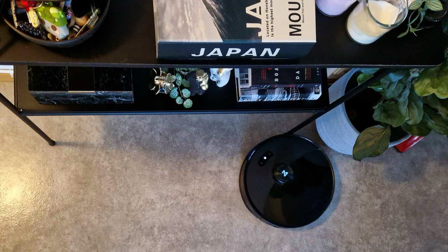 Roborock S8 MaxV Ultra puhdistamassa mattoa koristehyllyn vieressä