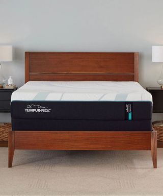 Tempur-Pedic ProAdapt Mattress on a wood bed frame against a white wall.