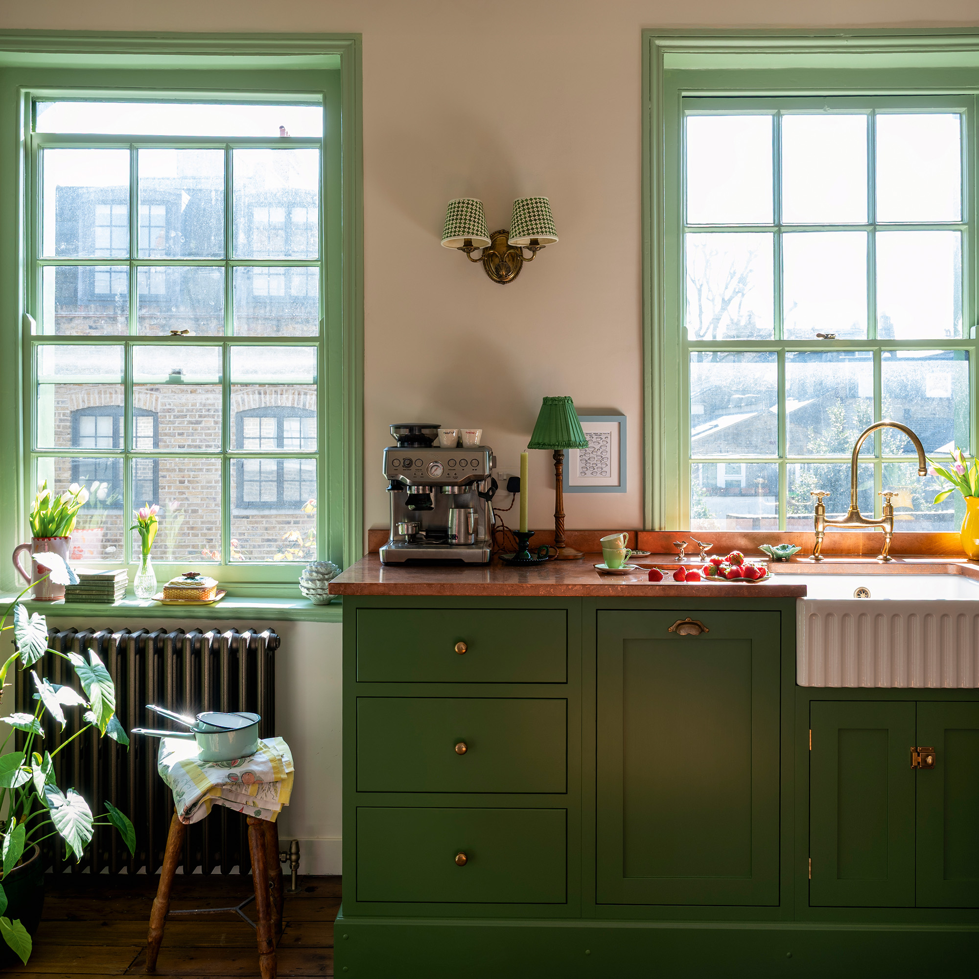 traditional kitchen with green cabinetry and woodwork, cream walls and wooden floors in a 17th-century london maisonette