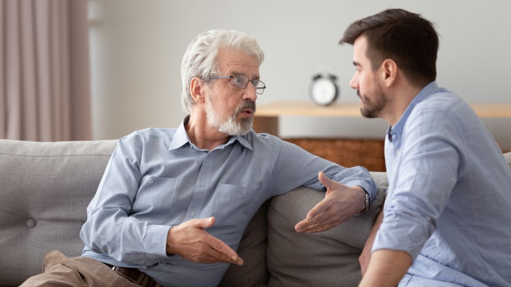 two men talking on a couch