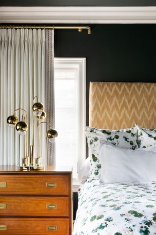 black bedroom with yellow headboard, globe table lamp, vintage bedside, drapes, floral bedding