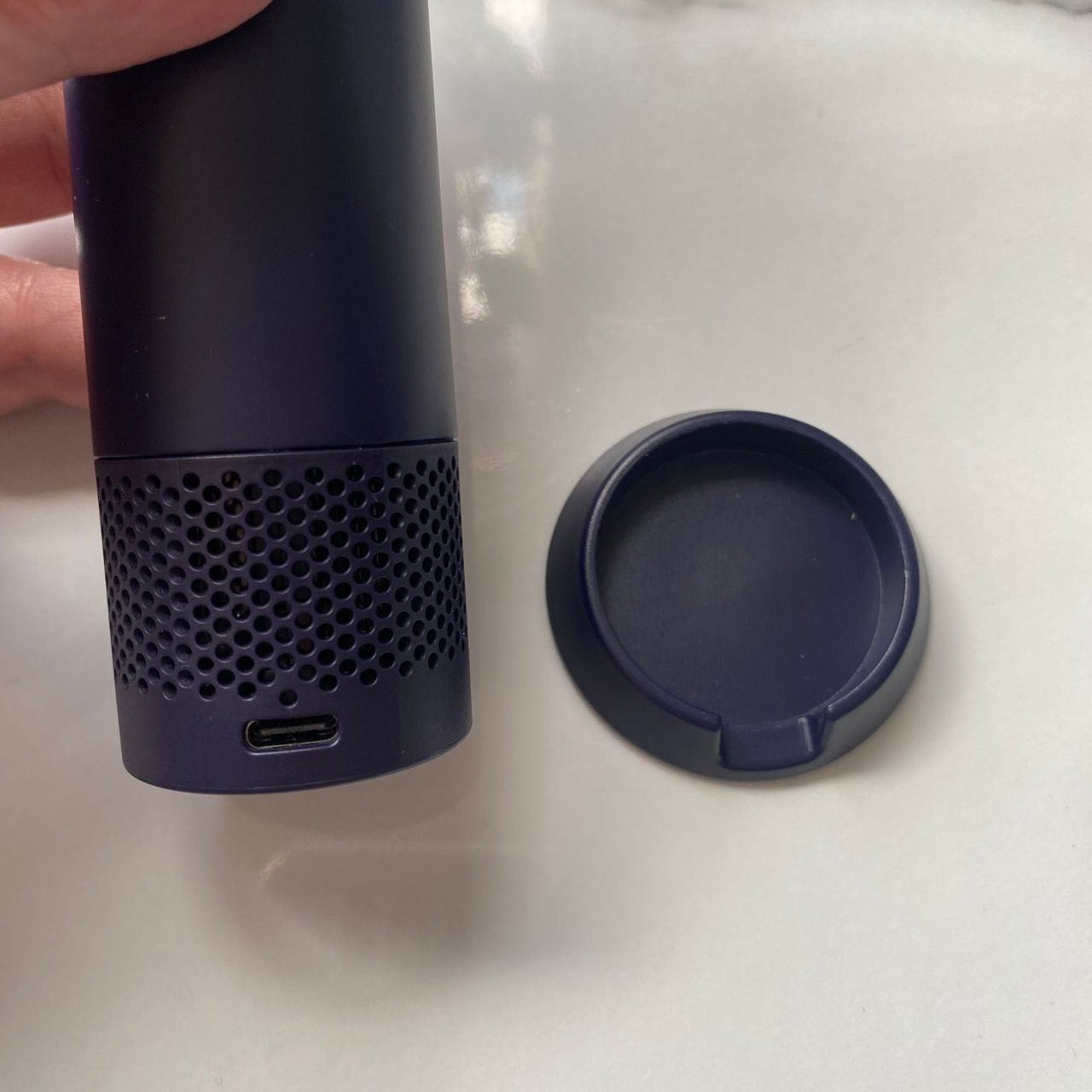 Base of the Dyson HushJet Mini Cool fan next to the charging stand on a marble look worktop