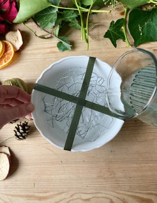 Christmas table centerpice step by step, bowl with chicken wire, jug pouring water in