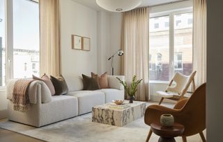 minimalist living room with neutral color scheme, boucle sofa, one sheepskin chair and one velvet chair