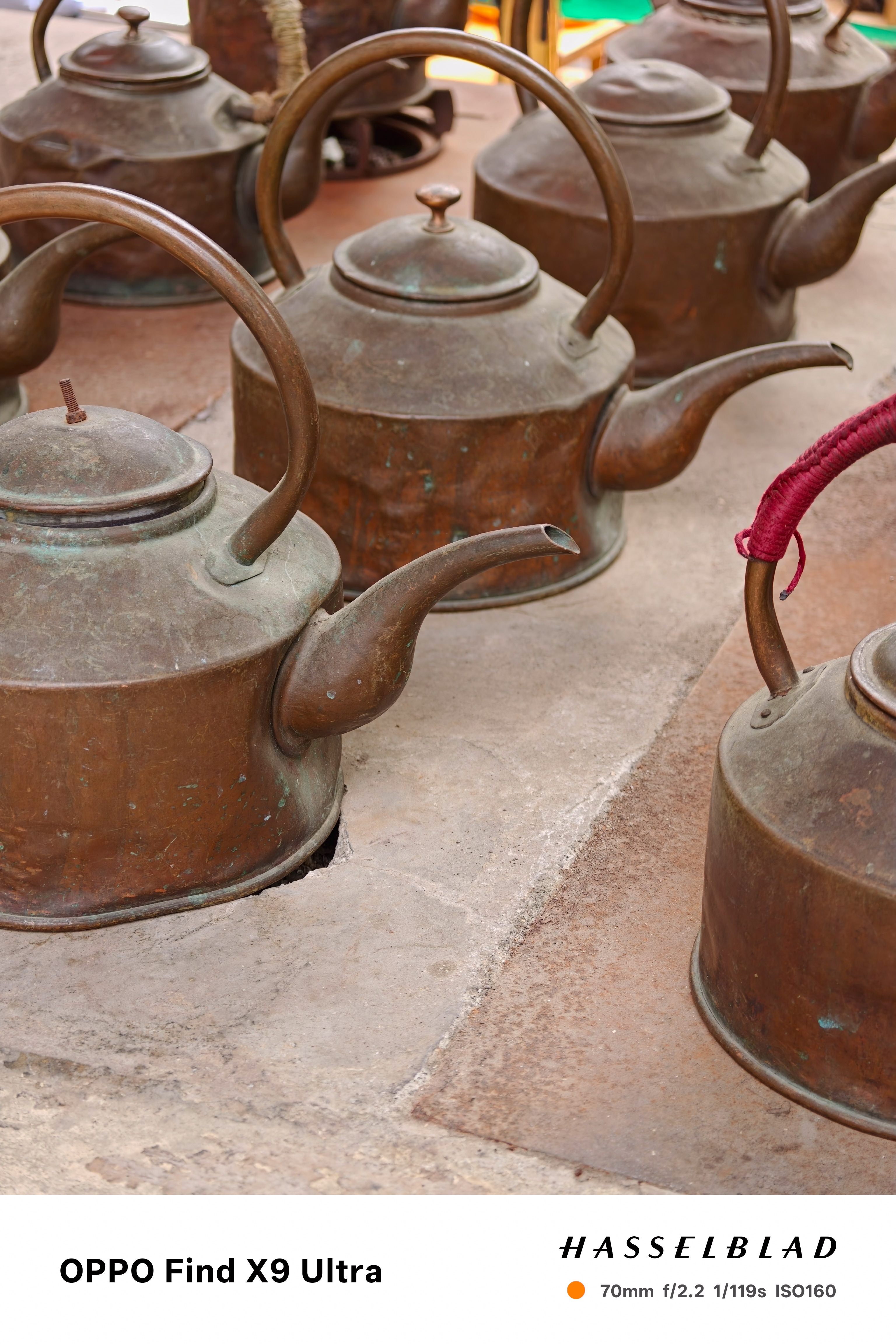 Group of weathered copper kettles arranged on a stone surface