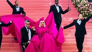 Lady Gaga flanked by men in tuxedos at the Met Gala