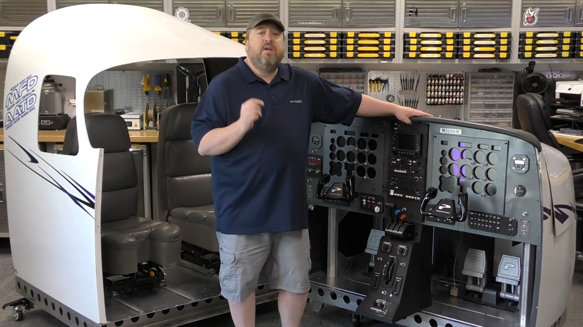 A screenshot from a YouTube video showing someone standing in front of a professional flight simulator setup