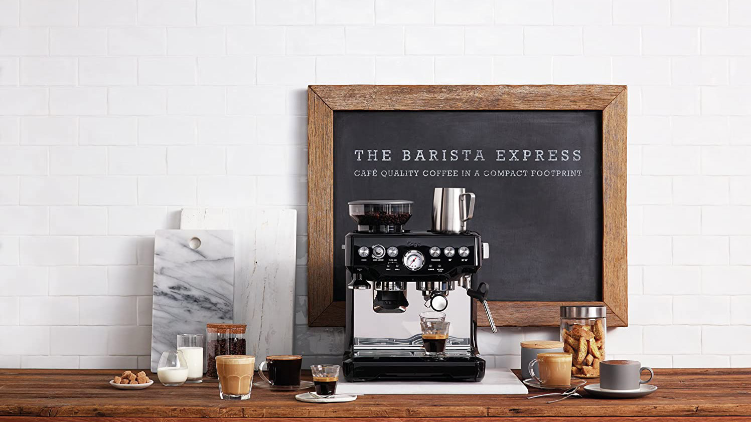 Sage Barista Express Espresso Machine puisella pöydällä valkoista seinää vasten