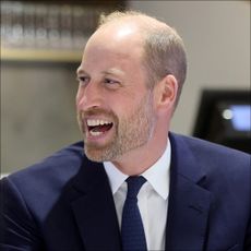 Prince William wears a navy suit and laughs