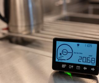 A smart meter in a kitchen next to a kettle