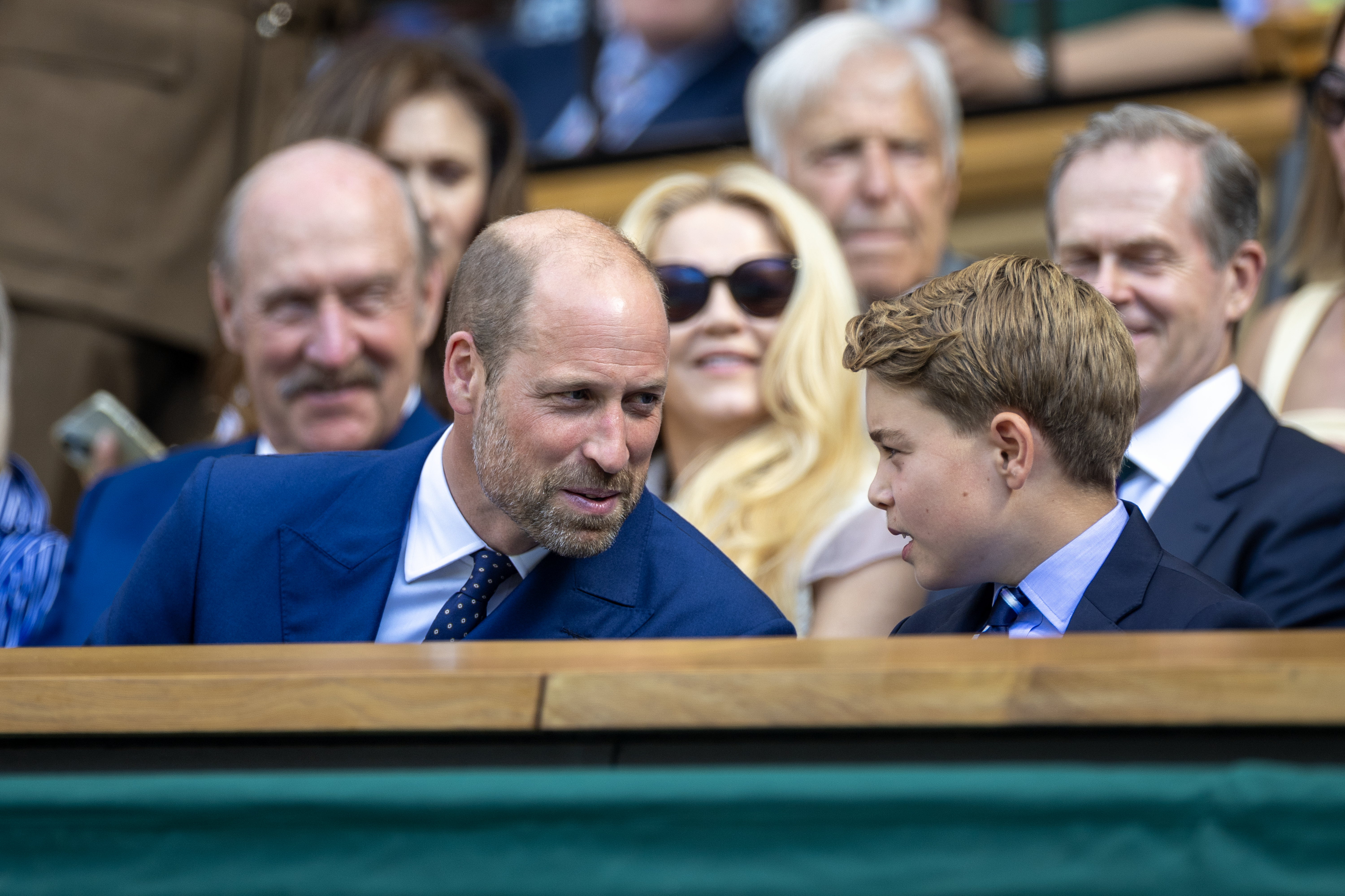 Prince William talking to Prince George at Wimbledon, sitting in the stands