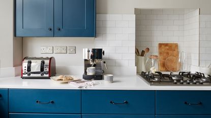 A blue kitchen with a toaster and a coffee machine