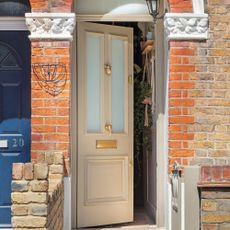 beige front door with gold hardware slightly open