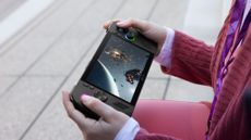 a person's hands holding a black PC gaming handheld