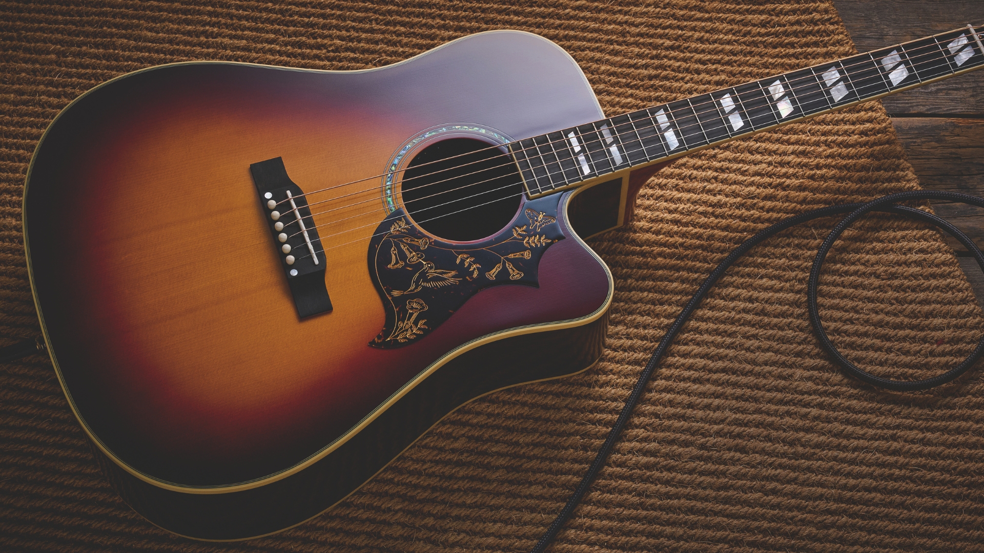 An Epiphone Hummingbird acoustic guitar on a yellow rug