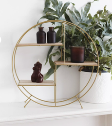 sass & belle antique gold round shelf with small candles and a plant in the background
