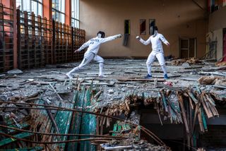 Two people fencing in a wrecked building
