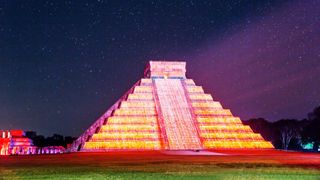 El Castillo pyramid illuminated at night under a starry sky in Chichen Itza, Mexico, one of the largest Maya cities.