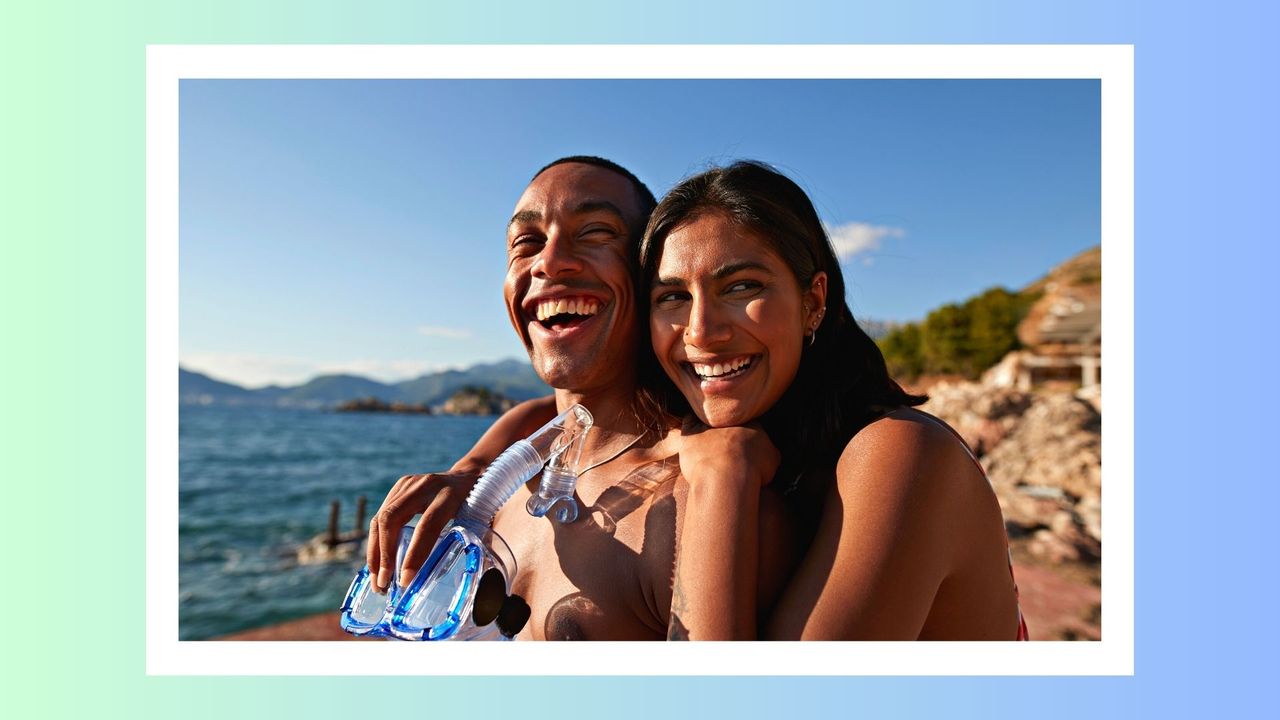 What are the &#039;Summer Fling Scaries&#039;? Pictured: Happy young woman with arm around boyfriend holding snorkel and scuba mask enjoying sunny day at beach