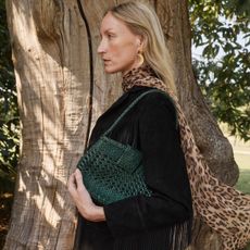 a model carrying a green woven leather handbag from the dragon diffusion x rixo collection