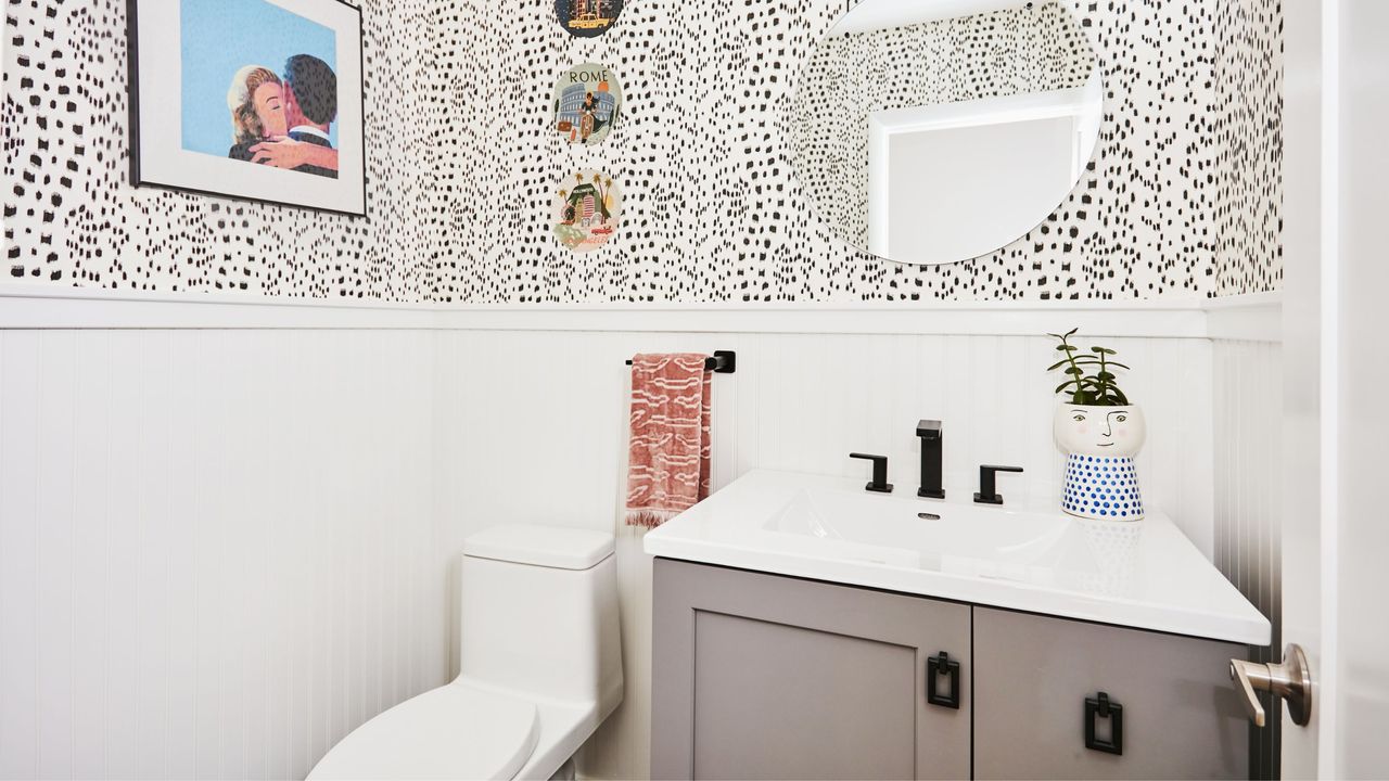 Black and white bathroom with wall art, wall plates, a toilet, and a sink