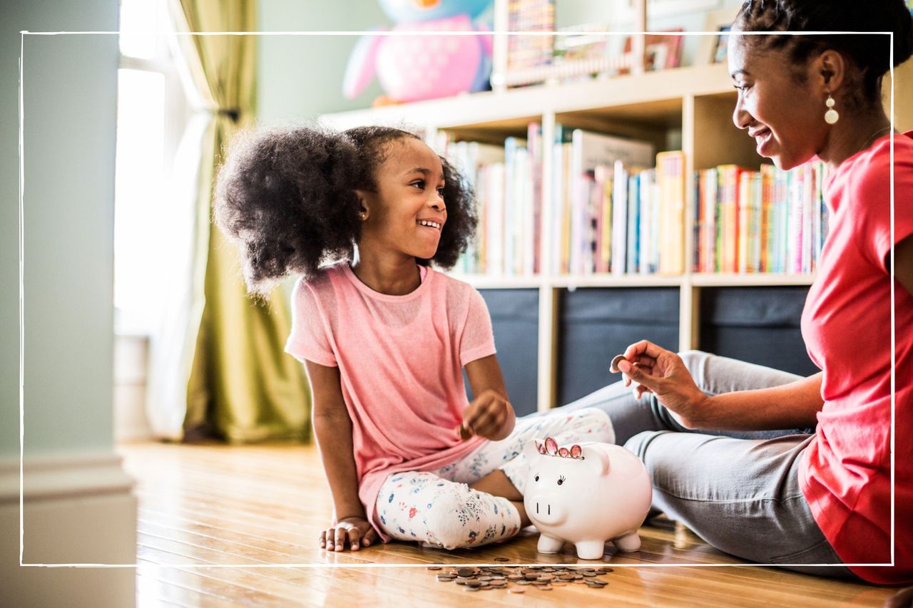 mother and daughter on the floor at home putting coins in a piggy bank