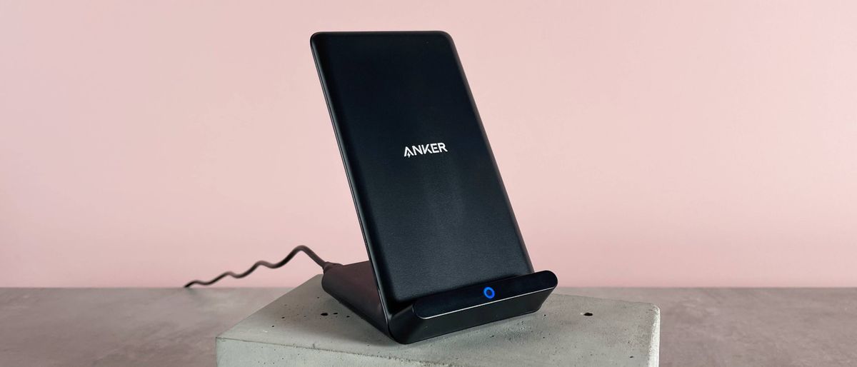 The Anker 313 Charger Stand is angled slightly to the right. It&#039;s sitting on a cement block against a pink background.