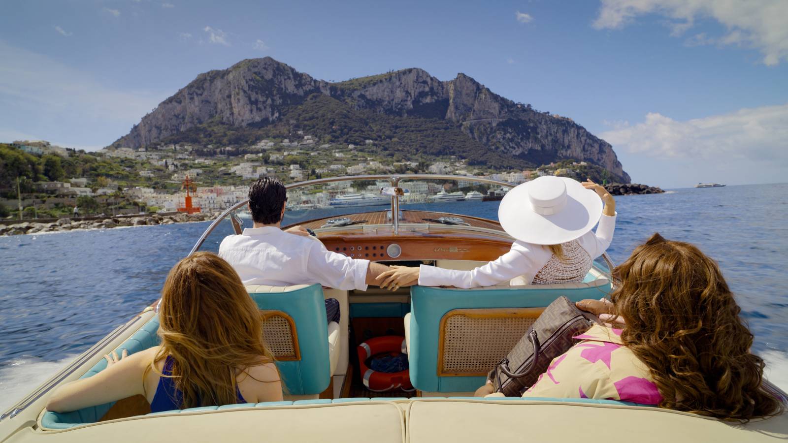 The cast of Another Simple Favor on a boat driving towards Capri.