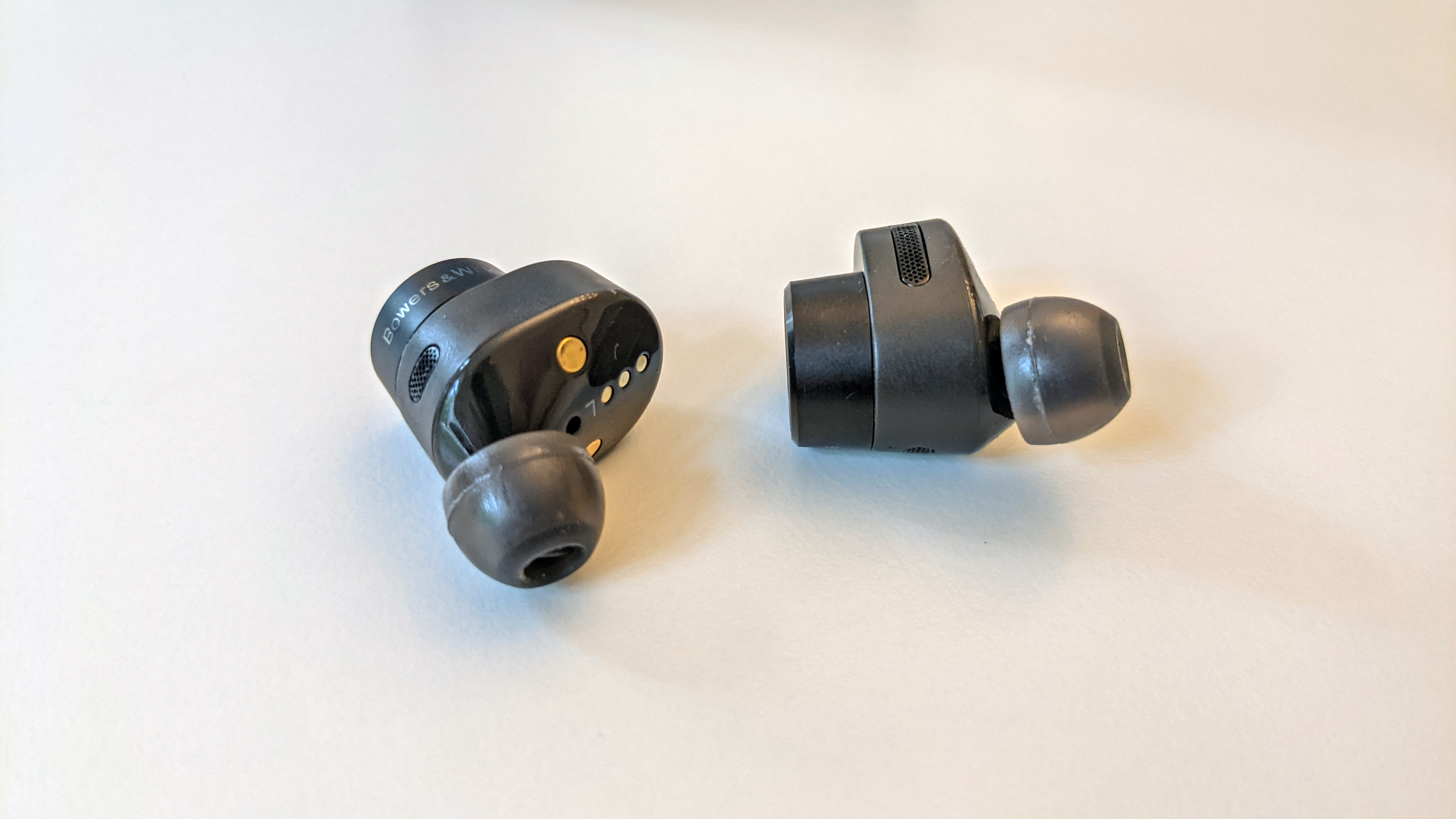 Anthrazitfarbene Bowers & Wilkins PI5 True Wireless liegen auf einem weißen Tisch