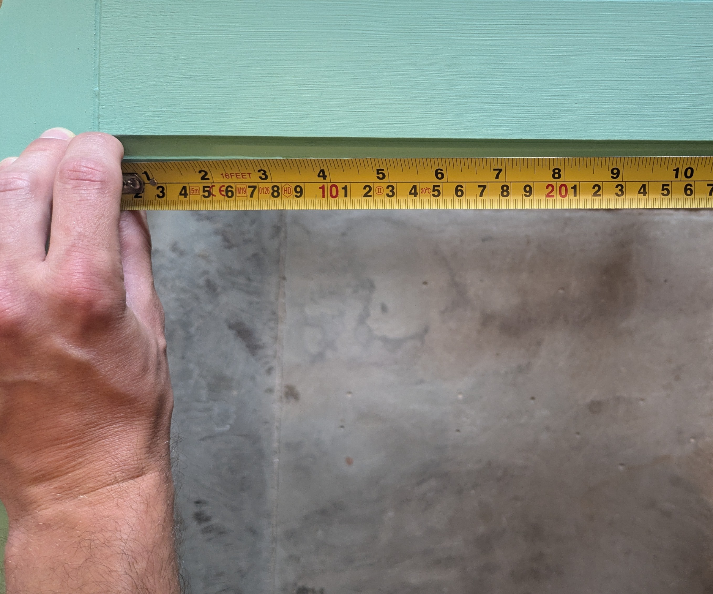 Using a tape measure to measure a wooden door section