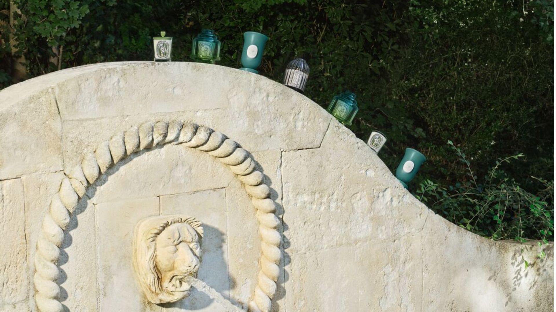 Pieces from the Diptyque Summer Garden Collection on a stone wall
