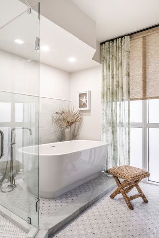 Bathroom with modern freestanding tub and geometric floor tiles and glass shower screen