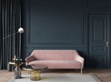 Painted deep black blue wall with light pink sofa in the foreground 