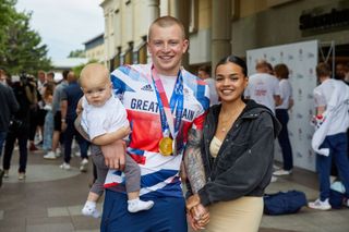 Adam Peaty poses for a photograph with Eirianedd Munro and their son George-Anderson Peaty
