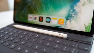 En vit Apple Pencil ligger ovanpå ett tangentbord på en iPad.